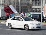 Children sticking out the sunroof with large flag